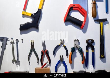 A set of different tools hanging on a white wall. Stock Photo