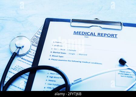 Patient treatment concept - medical report documents with pen and stethoscope in close-up (blue toned image) Stock Photo