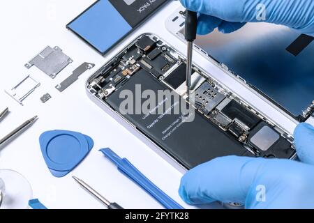 Professional occupation services concept - technician or engineer is repairing modern smartphone motherboard in a professional laboratory. Stock Photo