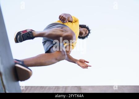 View from below of black man jumping on his run. Stock Photo