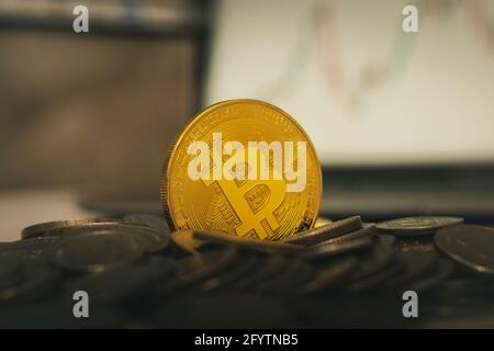 Bitcoins and virtual money concept. Gold bitcoins on a stack of coins with chart of growing and falling valuance of a cryptocurrency. Mining or blockc Stock Photo
