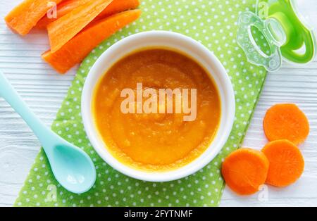 Baby carrot mashed with spoon in bowl, baby food Stock Photo