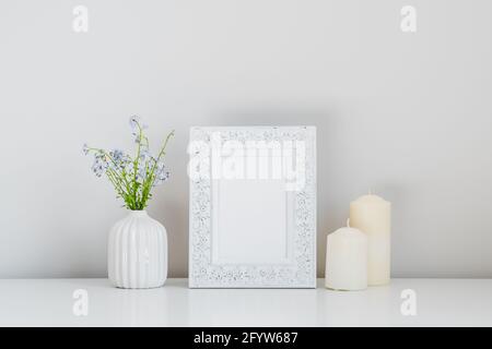 Photo frame mockup, candles, vase with spring flowers on white background. Stock Photo