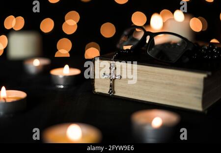 Rosary on holy bible with candlelights and bokeh lights background. Stock Photo