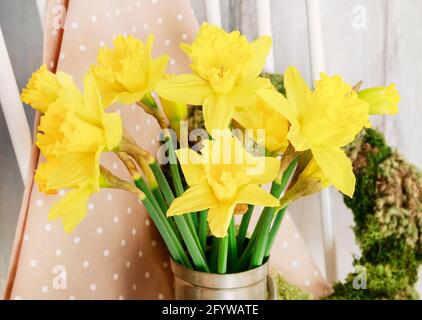 Easter home decoration with yellow daffodils in vintage silver can, lamb cake and moss wreath. Stock Photo