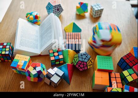 Different puzzle cubes and opened book on table Stock Photo