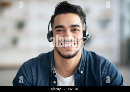 Closeup portrait of happy middle-eastern guy with headset having conversation Stock Photo