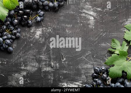 Frame made of Black grapes. Copy space for text or menu on black scuffed background. Black juicy grapes on vintage dark concrete background. Stock Photo
