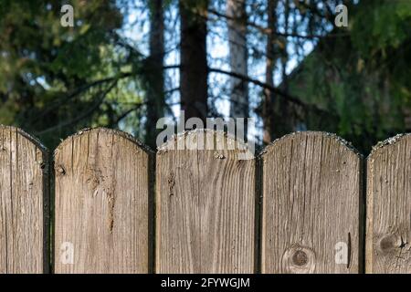 A wooden fence with planks rounded on top. Outdoors of day. Front view. Stock Photo