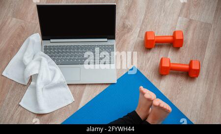 Towel dumbbells laptop Top view. Young woman do fitness workout, stretching exercises using laptop. Woman in sportswear make remote yoga exercise yoga Stock Photo
