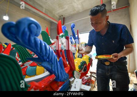 Qiandongnan, China's Guizhou Province. 30th May, 2021. A handicraftsman paints a dragon head for dragon boat in Chengguan Township, Shibing County of Qiandongnan Miao and Dong Autonomous Prefecture, southwest China's Guizhou Province, May 30, 2021. Handicraftsmen here are busy making dragon heads, a part of dragon boats for the contests during the upcoming Dragon Boat Festival. Credit: Liang Wen/Xinhua/Alamy Live News Stock Photo