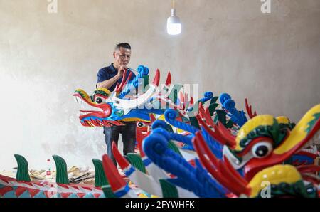 Qiandongnan, China's Guizhou Province. 30th May, 2021. A handicraftsman paints a dragon head for dragon boat in Chengguan Township, Shibing County of Qiandongnan Miao and Dong Autonomous Prefecture, southwest China's Guizhou Province, May 30, 2021. Handicraftsmen here are busy making dragon heads, a part of dragon boats for the contests during the upcoming Dragon Boat Festival. Credit: Cai Xingwen/Xinhua/Alamy Live News Stock Photo