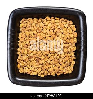 top view of whole fenugreek seeds in black bowl isolated on white background Stock Photo