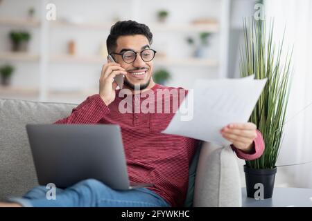 Middle-eastern man working online, using laptop and mobile phone Stock Photo