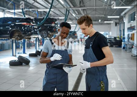 Two male mechanics talking in car service Stock Photo
