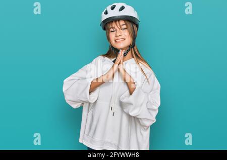 Teenager caucasian girl wearing bike helmet praying with hands together asking for forgiveness smiling confident. Stock Photo