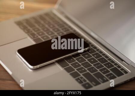Smartphone with black screen placed on laptop computer keyboard, closeup. Modern technologies in everyday life Stock Photo