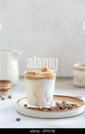 Iced Dalgona Coffee with fluffy sweet foam in a glass on a gray background. trendy summer drink. vertical image. copy space. Stock Photo