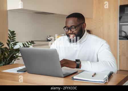 Smiling young afro american man freelancer studying or working online on laptop Stock Photo