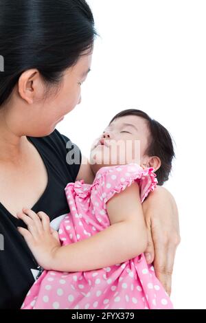 Sleepy little asian child with mom - cute daughter asleep on mother's hands, happy family concept. Mothers Day celebration. Studio shot. Stock Photo
