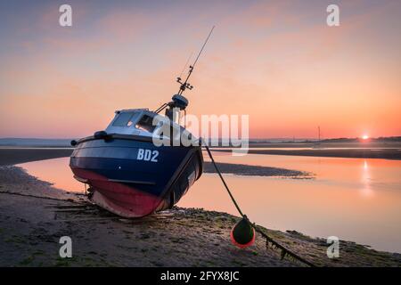 With a pastel sky overhead, the sunrises on a tranquil morning in late May, as the incoming tide creeps slowly along the shoreline towards one of the Stock Photo