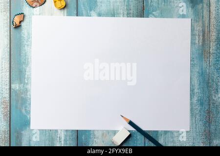 Top view of blank white paper page on blue wooden background with pencil, eraser, sharpener Stock Photo