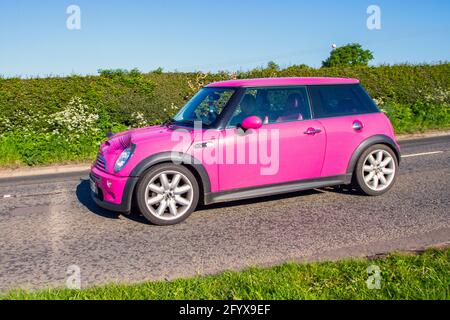 2004 pink Mini Cooper S, with eyebrows on headlights; Vehicular traffic, moving vehicles, cars, vehicle driving on UK roads, motors, motoring  en-route to Capesthorne Hall classic May car show, Cheshire, UK Stock Photo