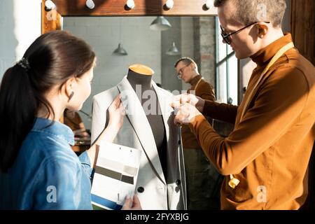 Two young fashion designers working over new jacket on dummy Stock Photo