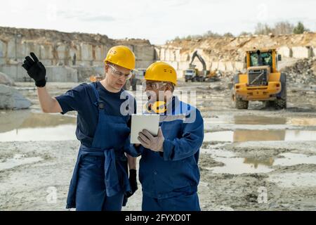 Contemporary builders discussing sketch in tablet during work Stock Photo