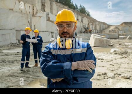 Young serious builder in workwear standing at workplace Stock Photo