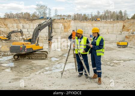 Male and female surveyors in uniform working on construction site Stock Photo