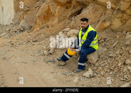 Restful builder in uniform having break at construction site Stock Photo