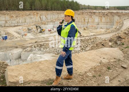 Female builder in uniform using walkie-talkie on construction site Stock Photo