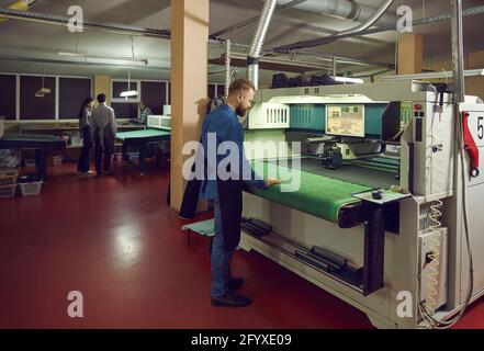 Worker using a cutting machine in a workshop of a footwear manufacturing factory Stock Photo