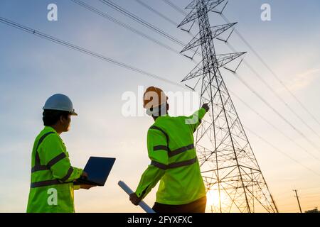Engineers and Technician working inspections at the electric power station to view the planning work by producing electricity high voltage electric tr Stock Photo