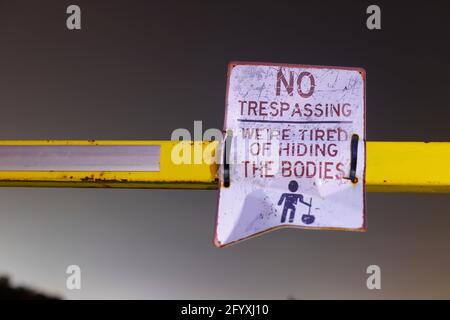 A humorous sign warning people not to trespass. The sign reads 'No Trespassing, we're tired of hiding the bodies. Stock Photo