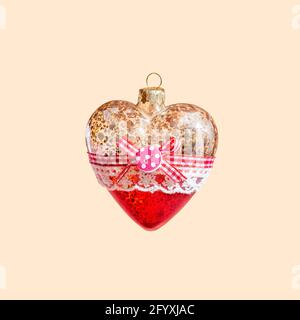 Glass heart Christmas tree toy soars in the air on a pastel beige background. Concept New Year Stock Photo