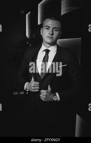 A grayscale shot of a young elegant Caucasian male wearing an expensive suit at an event Stock Photo