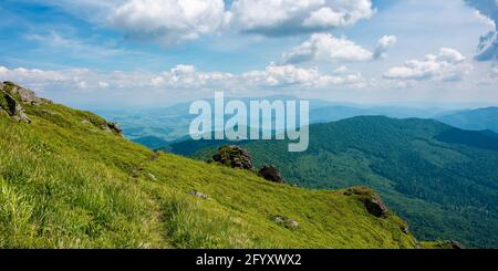 view from pikui mountain. huge stones on the grassy slopes. summer landscape of carpathian mountains. borzhava ridge in the distancee beneath a sky wi Stock Photo