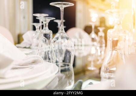 Close-up of festive setting in luxury restaurant. Glasses, plates, cutlery on mirror table. Selective soft focus, lens flare Stock Photo