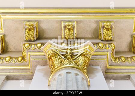 Close-up decorative gold stucco on the ceiling fillet in luxurious expensive interior of a large baroque royal living room. antique molding, gold trim. Stock Photo