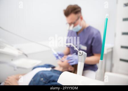 Selective focus on dental equipment, male dentist working with patient on background Stock Photo