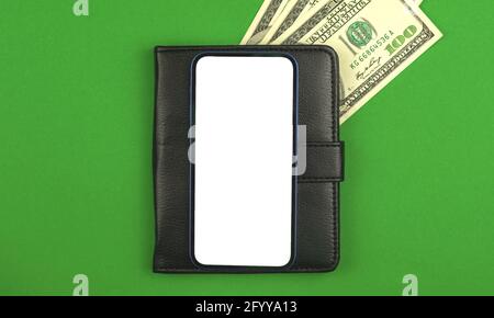 Mobile phone mockup screen with background of black leather and money on a green office table, business and finance application concept and template Stock Photo