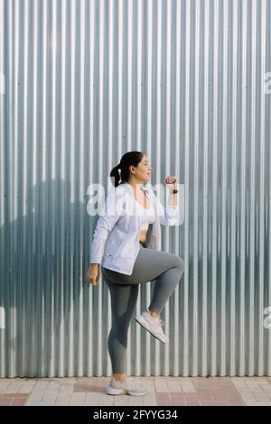 Side view full body of plus size active young ethnic female athlete in sportswear doing steps exercise while working out on city street in sunny morni Stock Photo