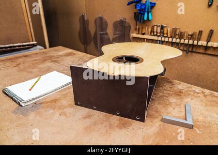 Classical musical instrument piece on wooden table with notebook and square against professional manual tools in workroom Stock Photo