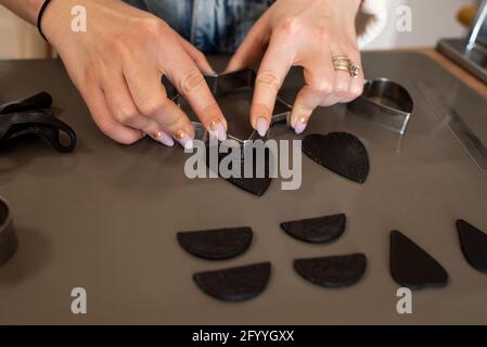 From above crop unrecognizable female jewelry maker forming details of black clay while working in light craftsmanship Stock Photo