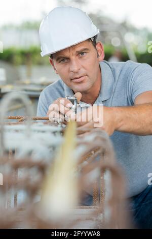 man measuring off metal bar outdoors Stock Photo