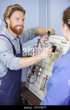 engineer and apprentice examining component in factory Stock Photo