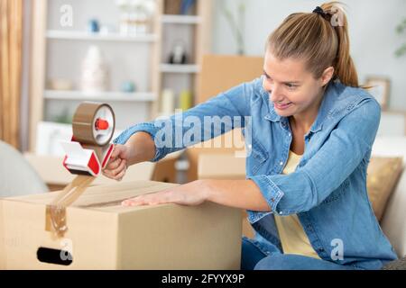 close-up of female sealing cardboard box with adhesive tape Stock Photo