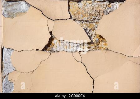 crumbling wall of a building old architecture stone facade with cracked plaster texture closeup. Stock Photo